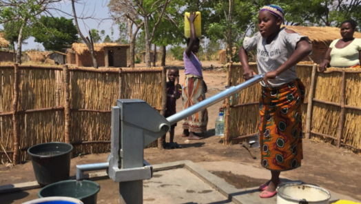 A girl in East Africa pumps water from a well